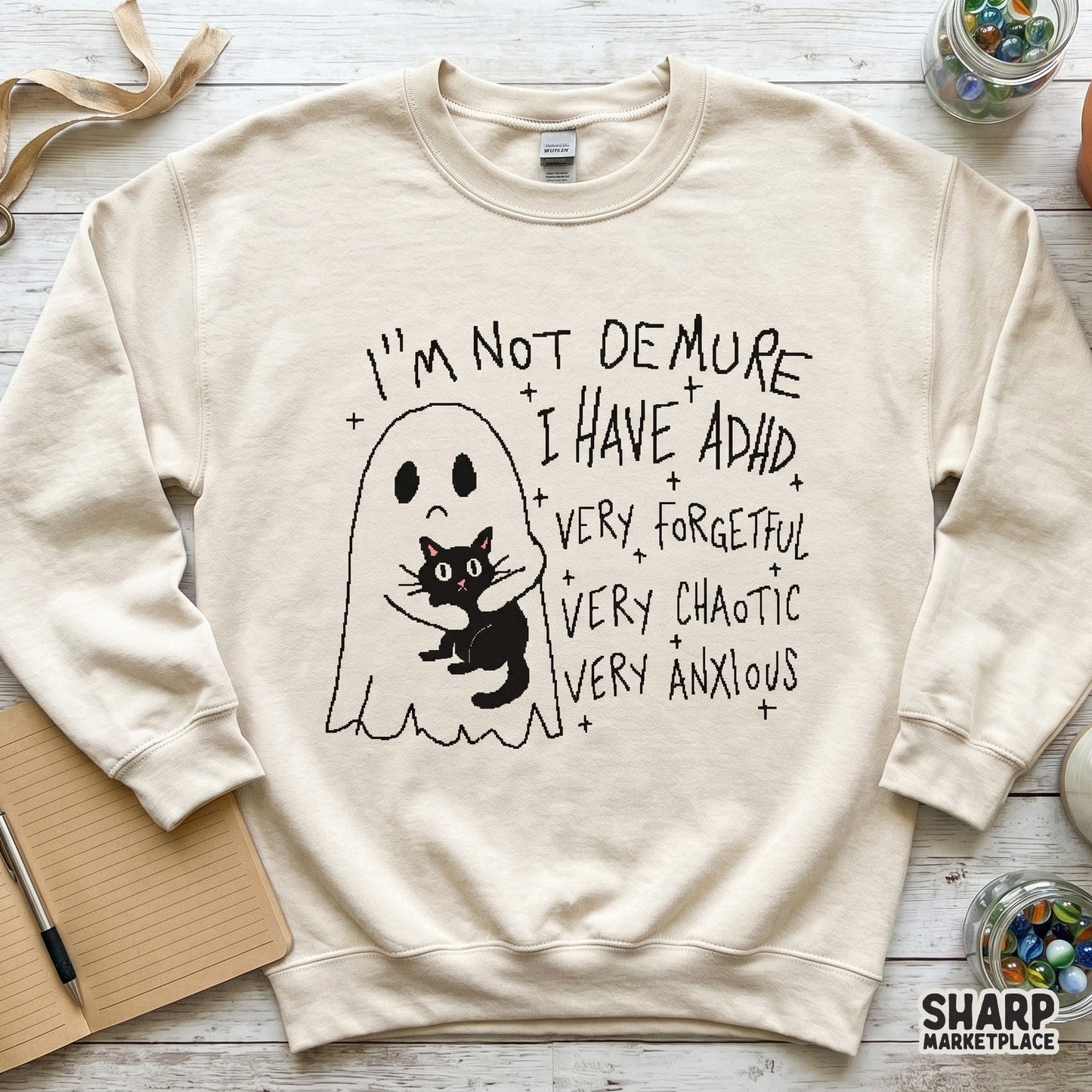 Digital design on a cream-colored sweatshirt featuring a ghost hugging a black cat with sarcastic ADHD text and star accents in a charcoal line art style.
