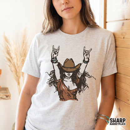 Trendy western cowgirl illustration with raised hands, featured as a digital graphic on a light heather gray t-shirt for country concert style.
