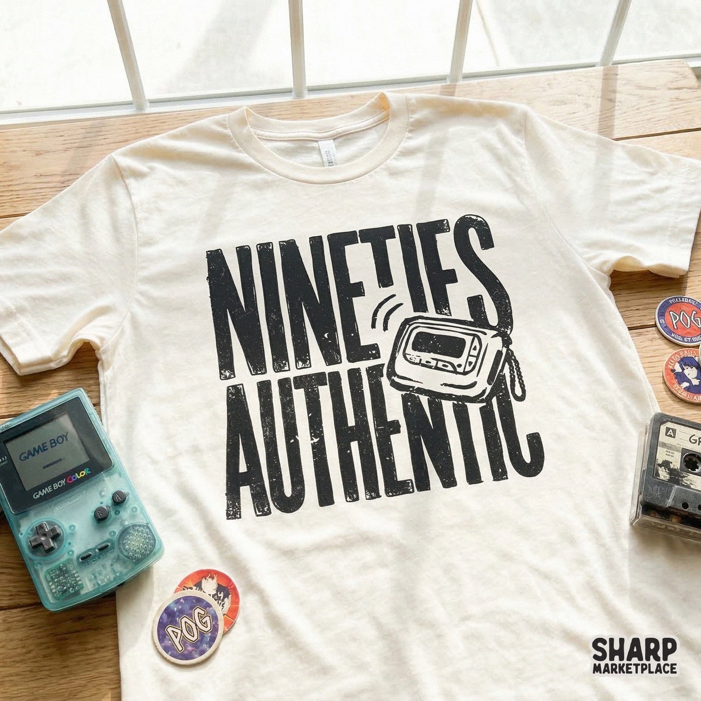 A cream-colored t-shirt displaying a black, textured graphic of a 90s pager and the words Nineties Authentic, ideal for retro apparel projects.