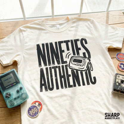 A cream-colored t-shirt displaying a black, textured graphic of a 90s pager and the words Nineties Authentic, ideal for retro apparel projects.