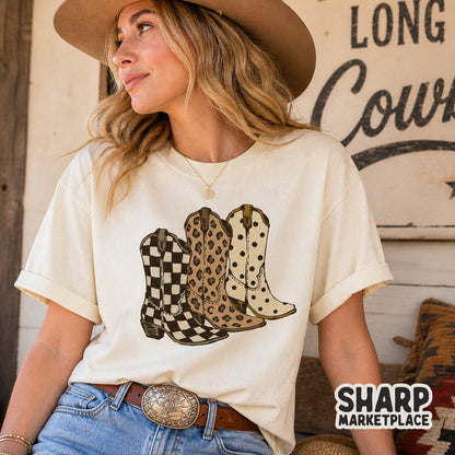 Trendy western cowgirl boots sublimation design with checker, leopard, and polka dot patterns displayed on a cream colored t-shirt.