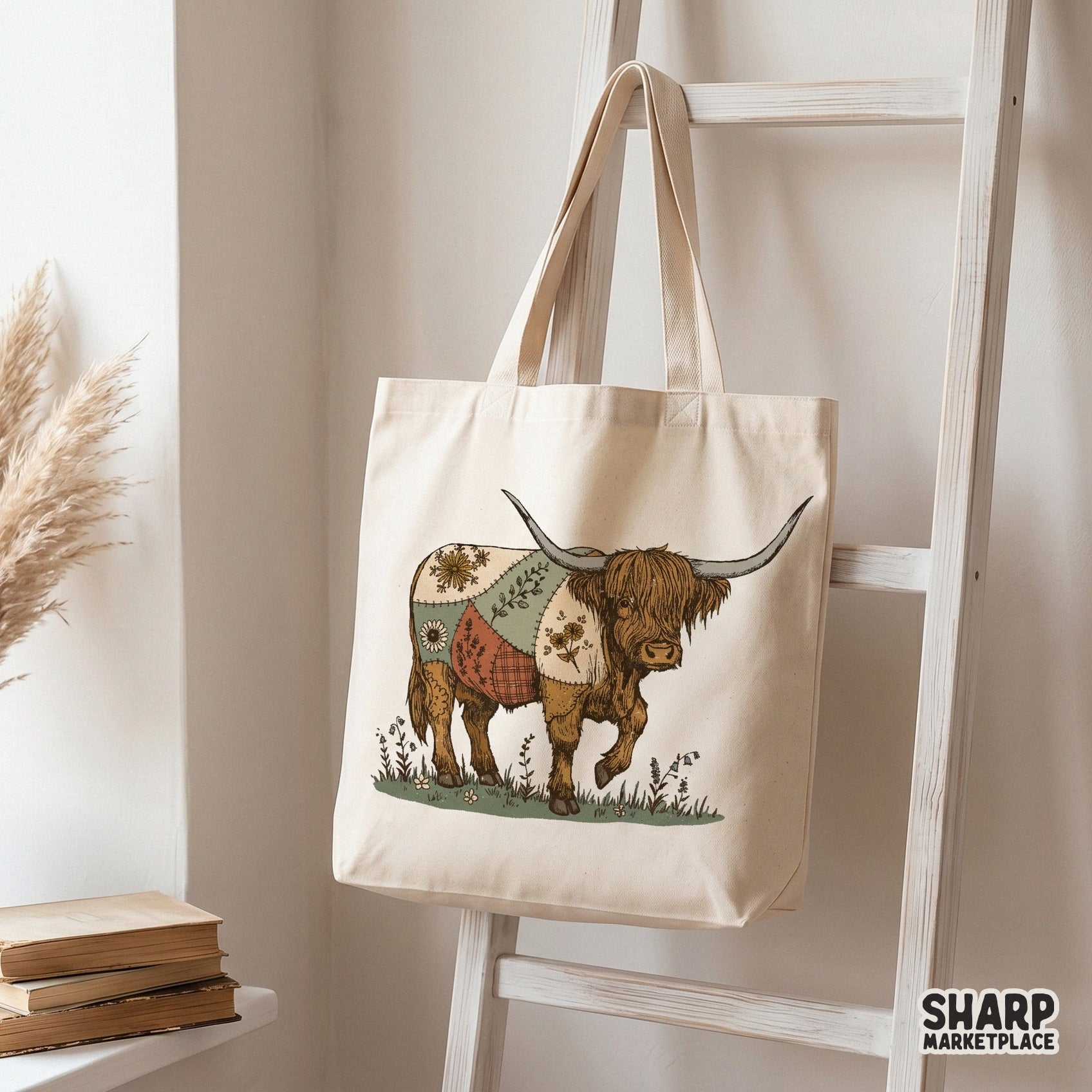 Boho style highland cow digital art featuring a patterned fabric blanket and prairie flowers, displayed on a canvas tote bag for custom apparel.