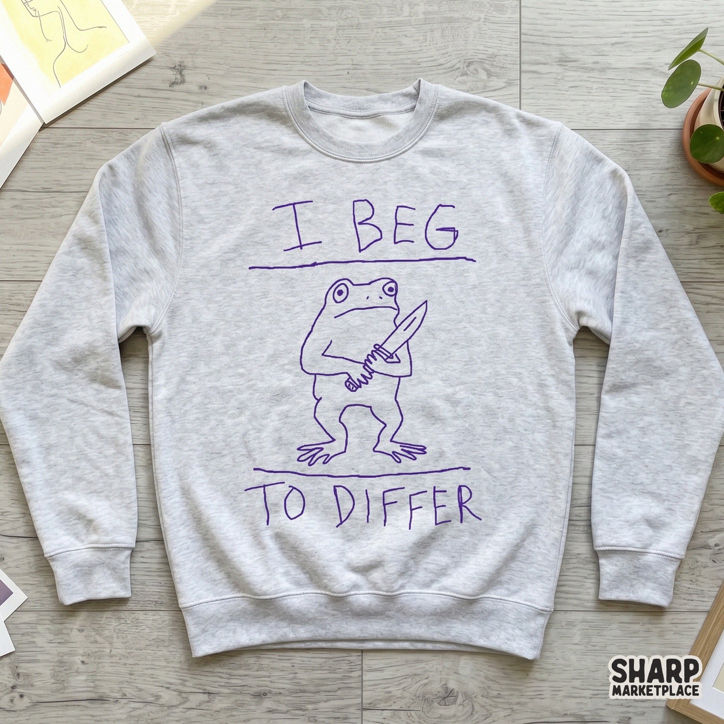 Minimalist purple doodle of a frog wielding a blade with the phrase I Beg To Differ, ideal for sarcastic t-shirt prints and custom DIY gift projects.