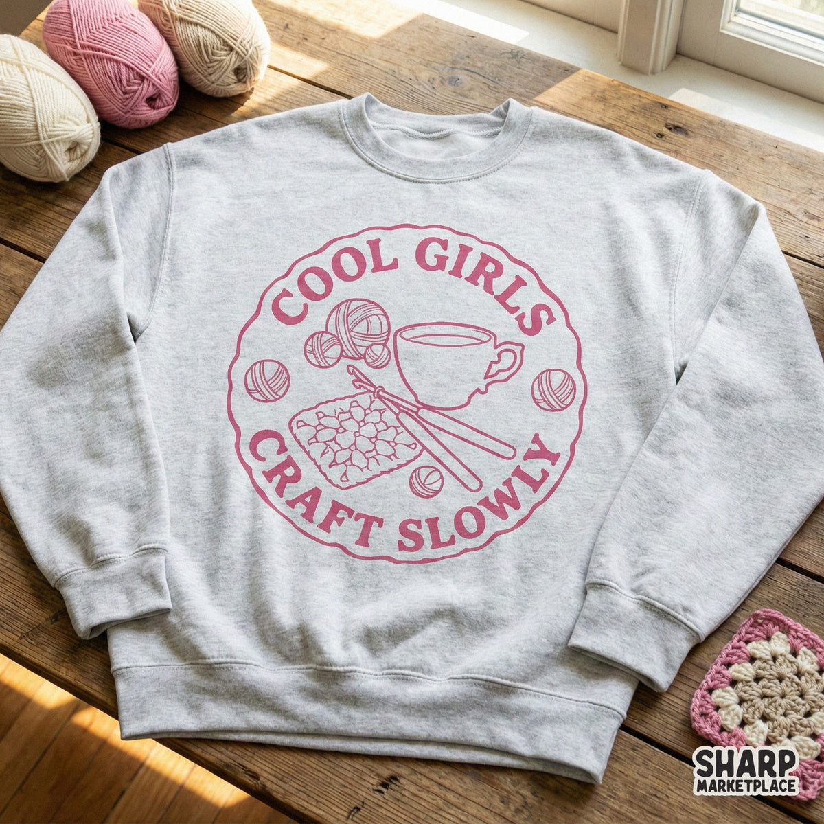 Retro-style dusty rose graphic featuring crochet supplies and coffee, displayed on a light gray crewneck sweatshirt for apparel printing.