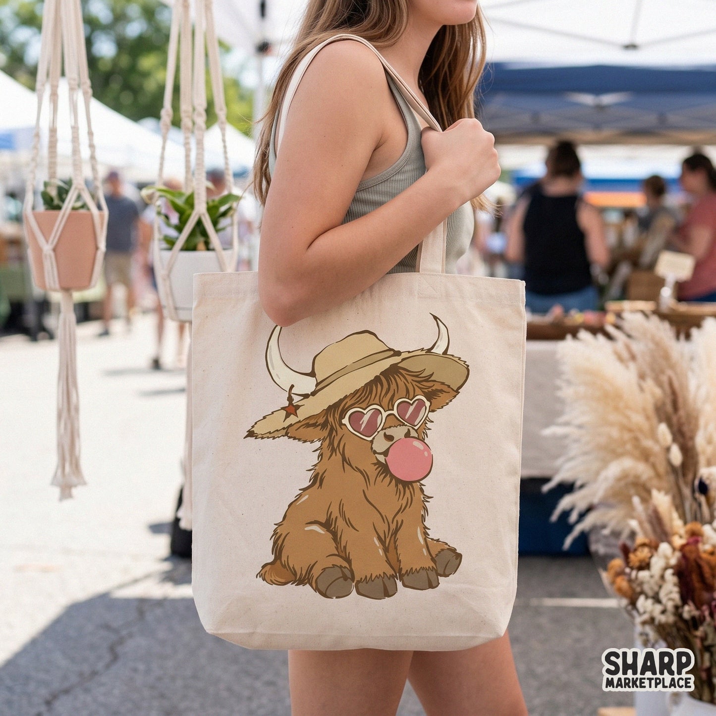 Trendy western highland cow graphic featuring a shaggy calf with heart sunglasses and bubblegum, displayed on a canvas tote bag mockup.