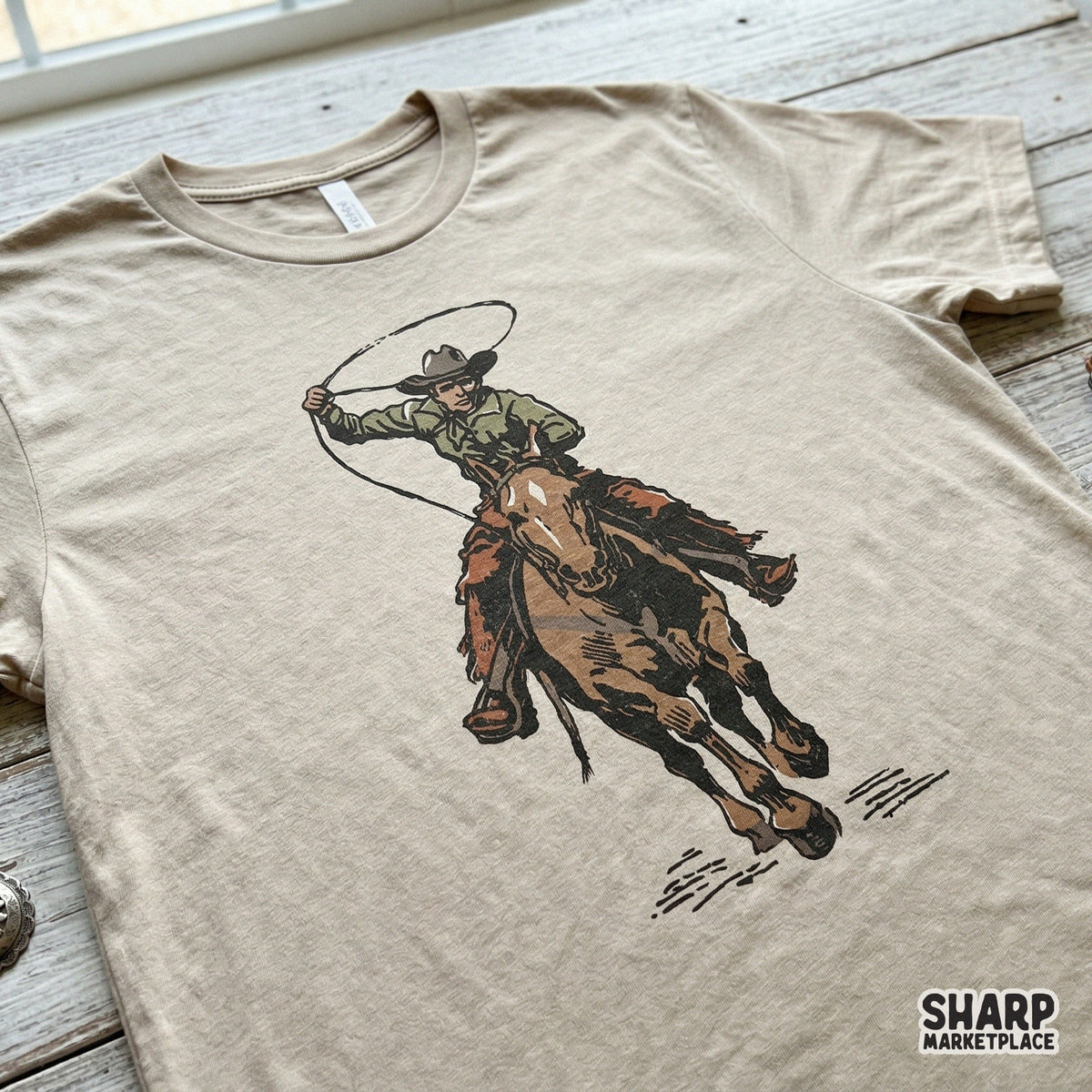 Detailed digital illustration of a rodeo rider on a galloping horse with a rope, presented on a beige t-shirt mockup for custom western clothing design.