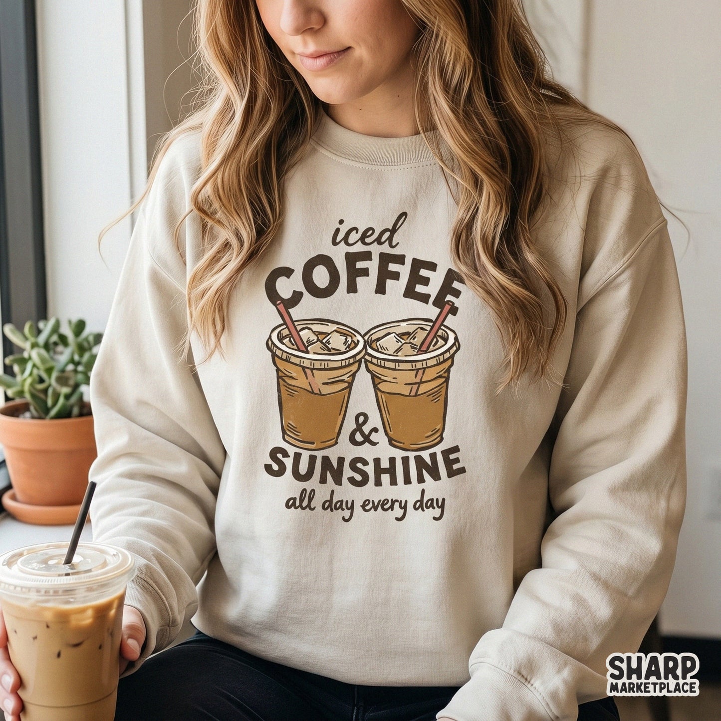 Trendy iced coffee and sunshine digital artwork on a beige sweatshirt, featuring hand-drawn coffee cups and playful vintage-style typography.