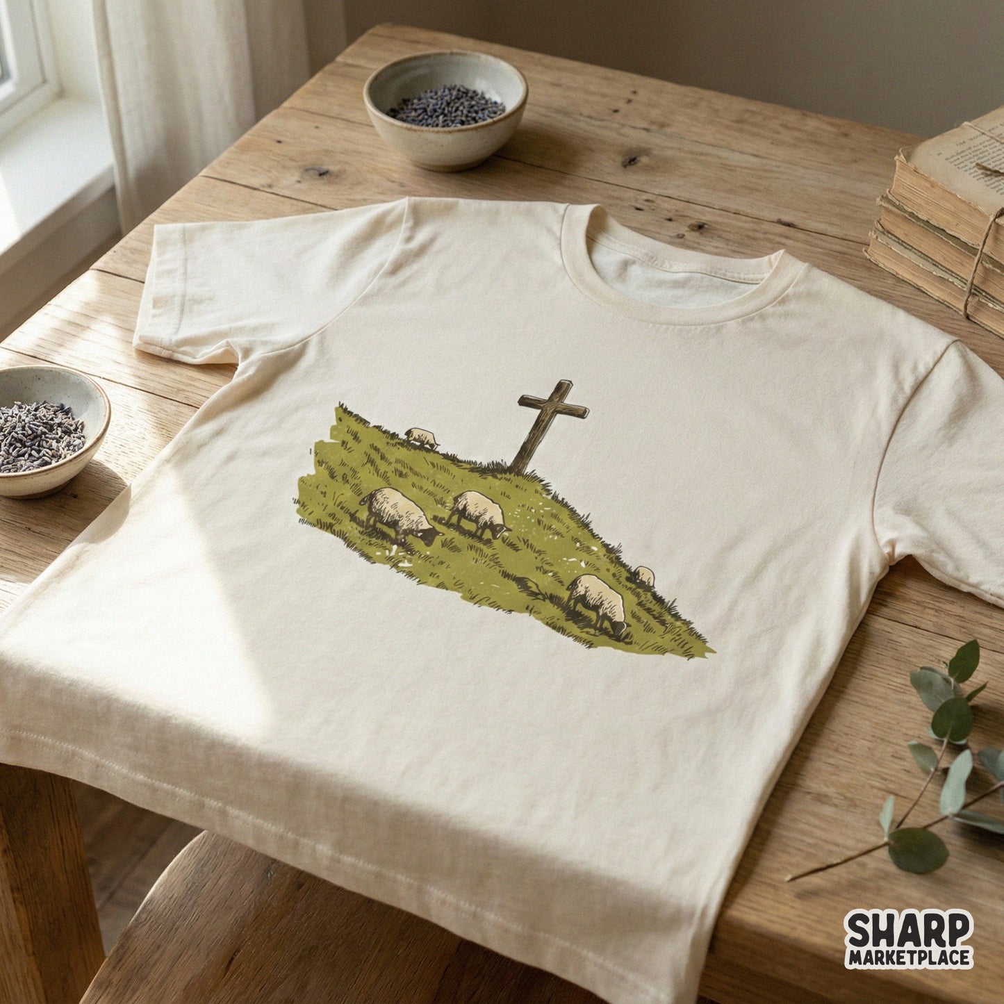 A vintage-style illustration of a wooden cross and grazing sheep on a hillside, presented as a digital graphic for custom apparel and sublimation.