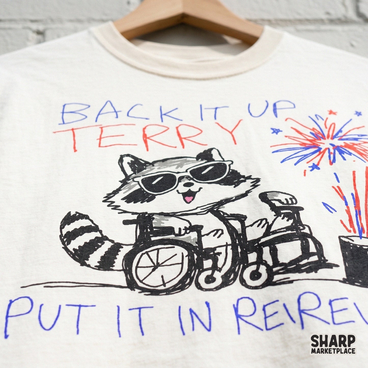 Funny raccoon in a wheelchair with red and blue fireworks and star accents, featuring the text Back It Up Terry Put It In Reverse for sublimation.