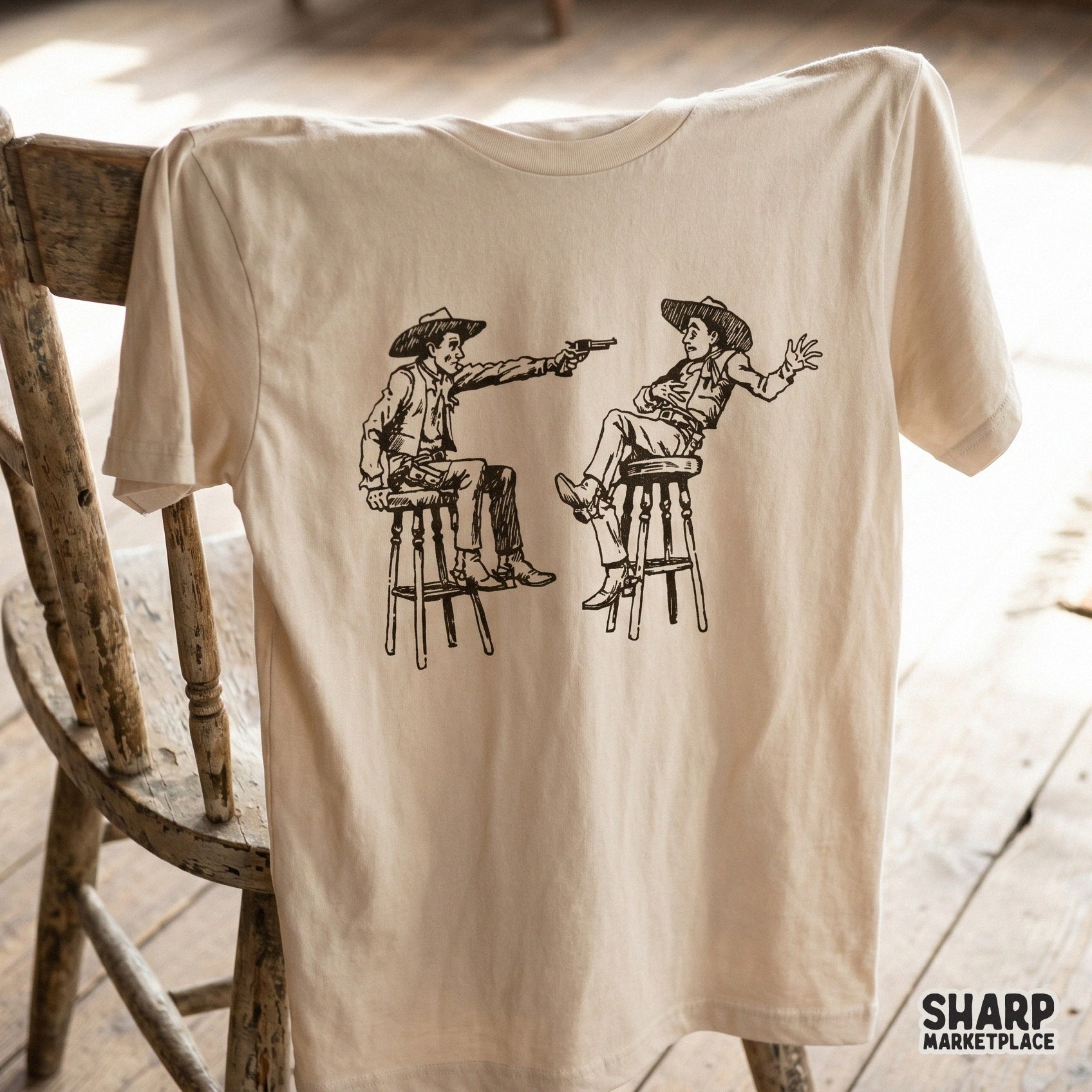 Vintage western saloon standoff illustration featuring two cowboys on barstools, printed in black ink on a light beige t-shirt mockup.