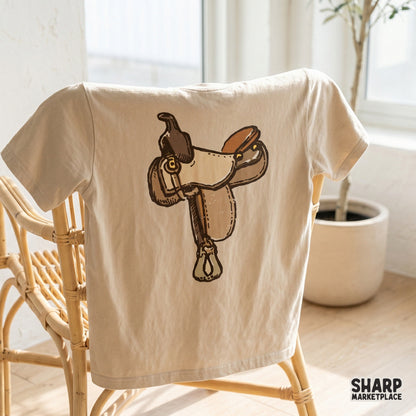 Rustic western saddle artwork with bold outlines and earthy colors, designed for versatile use in DIY country-style projects, apparel, and transfers.