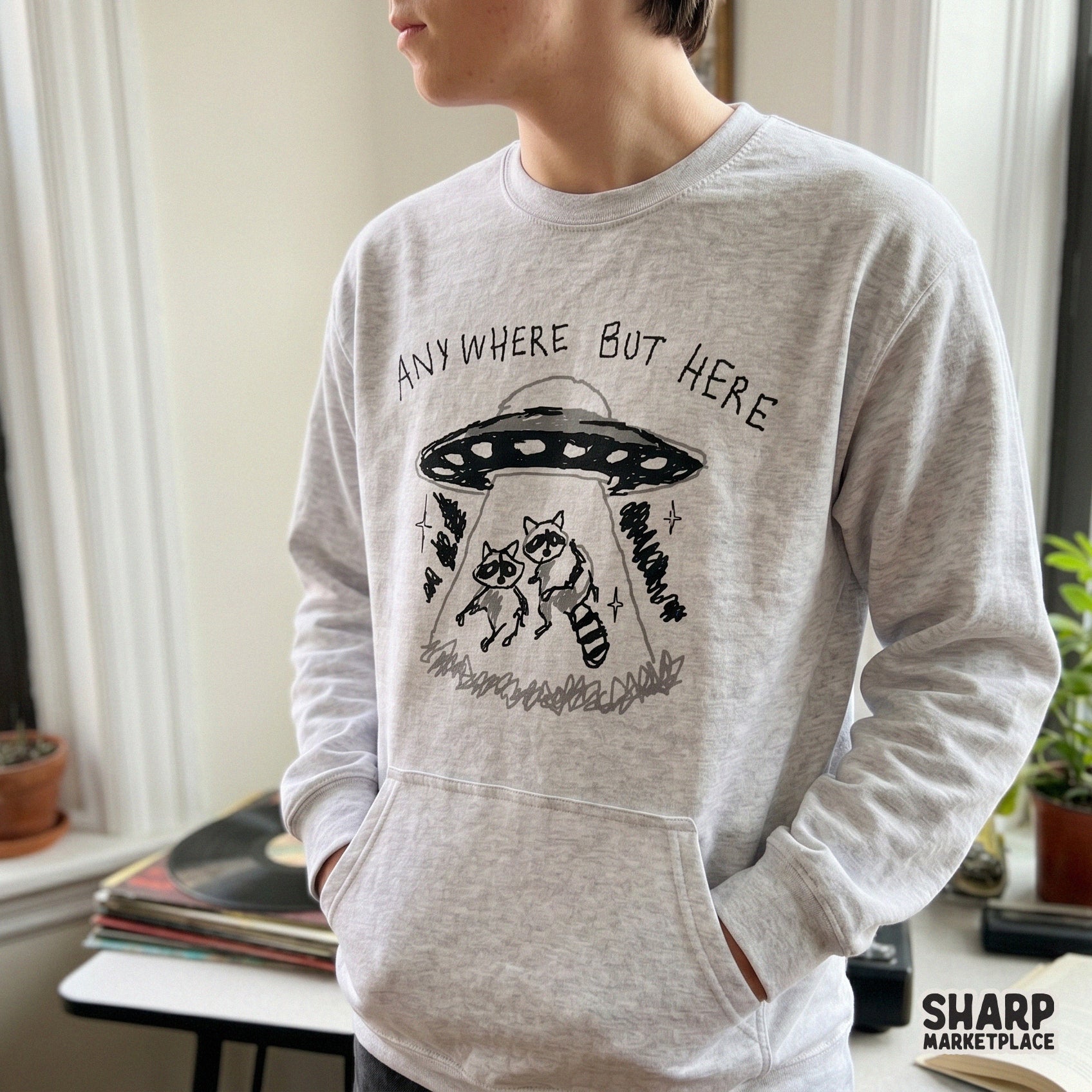 Funny raccoon abduction illustration with the text Anywhere But Here, designed as a transparent PNG for apparel, tumblers, and creative crafts.