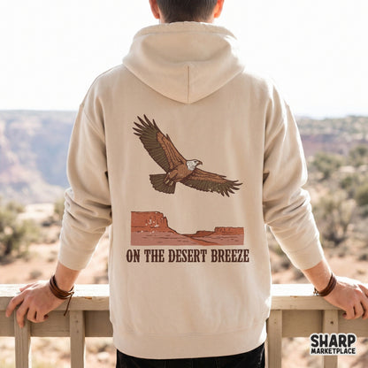 Beige hoodie mockup displaying a vintage southwest design of a soaring eagle over a red mesa canyon with the text On The Desert Breeze.