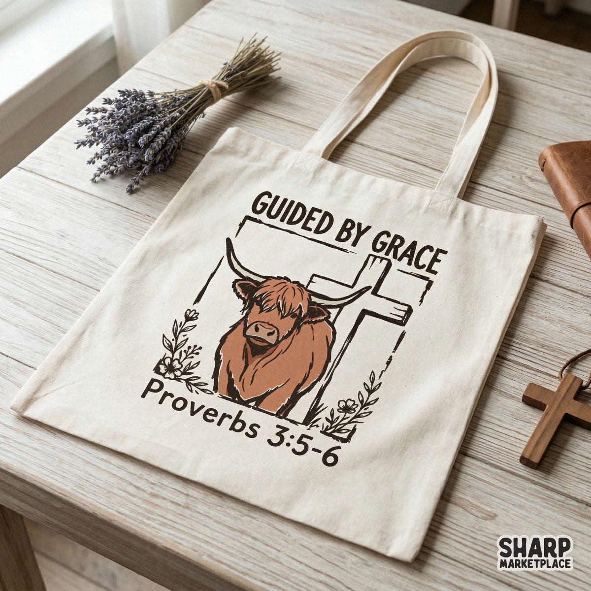 Digital design of a highland cow standing before a rustic cross with floral elements and the text Guided By Grace Proverbs 3:5-6 on a tote bag.