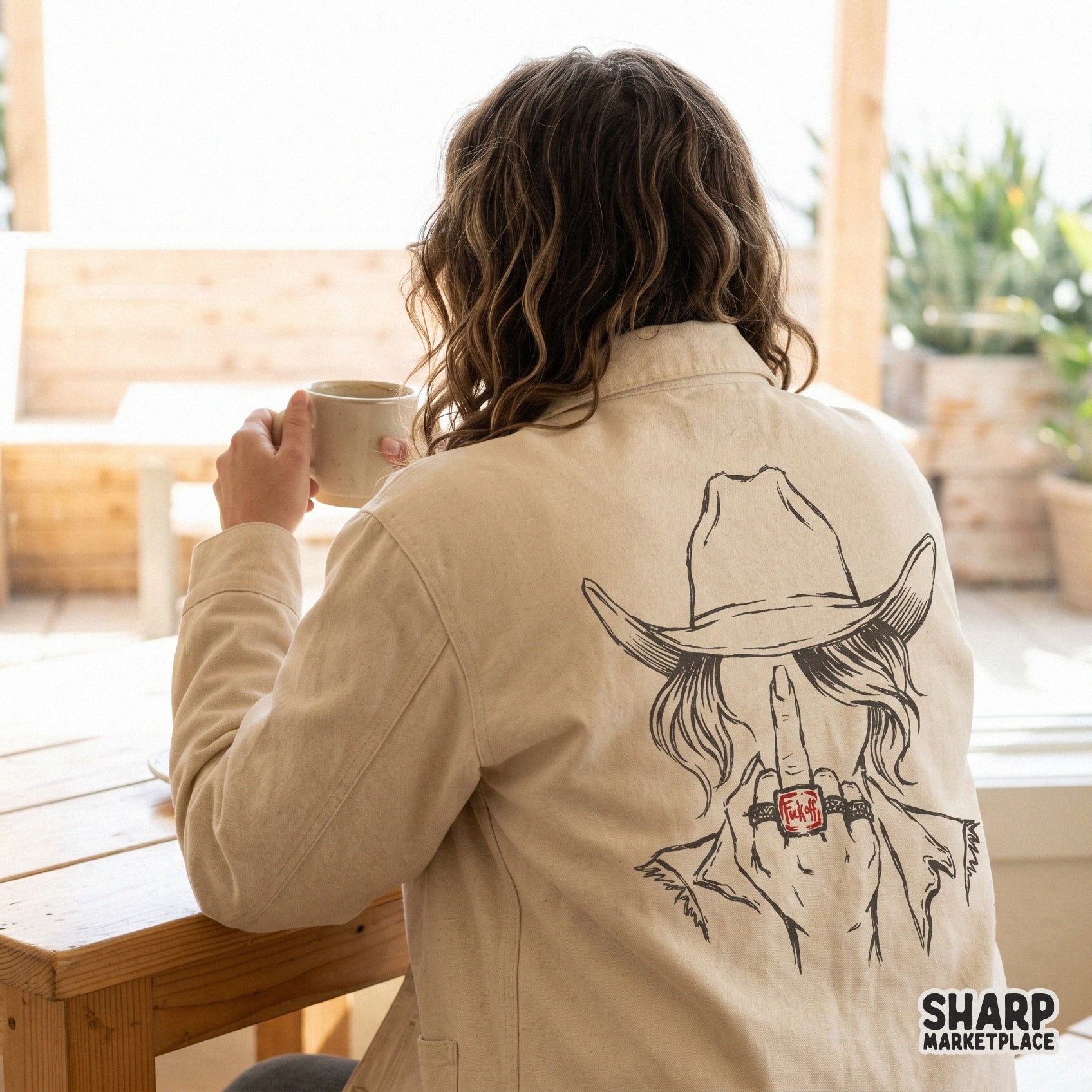 Edgy western cowgirl illustration featuring a middle finger gesture and a bold red ring, displayed as a graphic print on the back of a shirt.