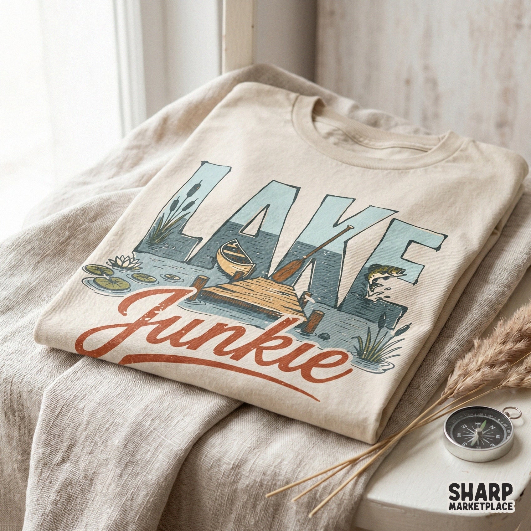 Vintage style Lake Junkie graphic printed on a folded t-shirt, showcasing a canoe, dock, and fishing scene for custom summer clothing projects.