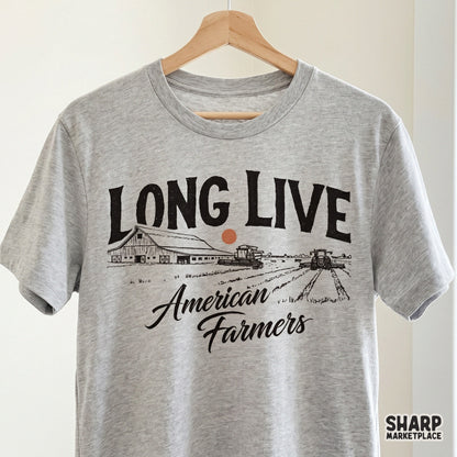 Rustic farm life graphic on a grey t-shirt mockup showing a barn, tractor, and combine harvester with vintage typography for country apparel.